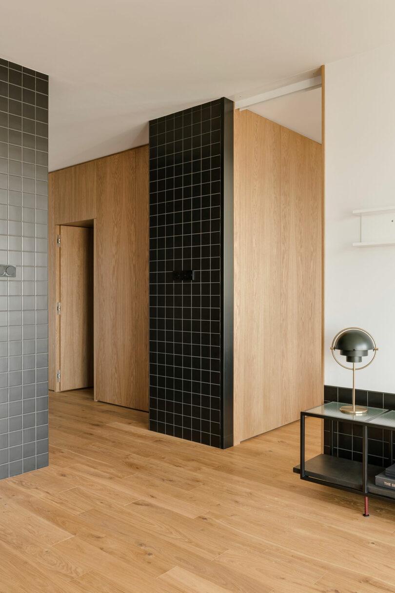 partial angled view of modern living space with black tiled cabinet by bedroom door