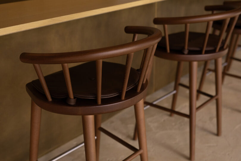 Detail of two of the eight dark walnut Windor wood chairs.
