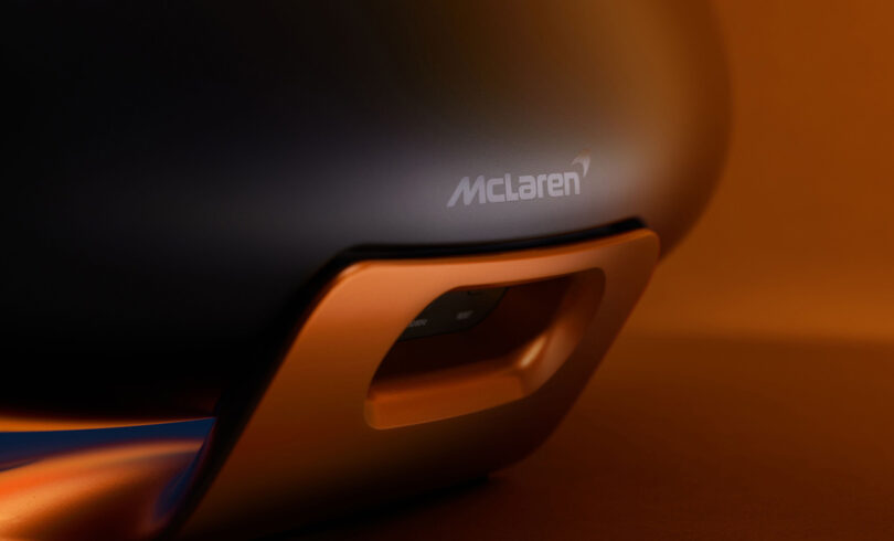 Close up of McLaren logo adorning back of Bowers & Wilkins Zeppelin McLaren Edition wireless speaker, finished in Galvanic Grey body and Papaya Orange.