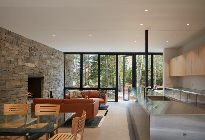 interior shot of modern living room with stone walls, industrial kitchen, and orange leather seating