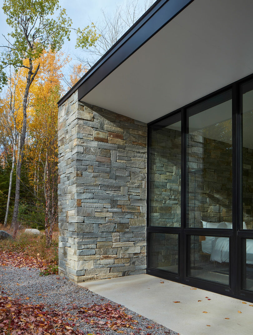 closeup corner shot of stone and glass lake house in woods