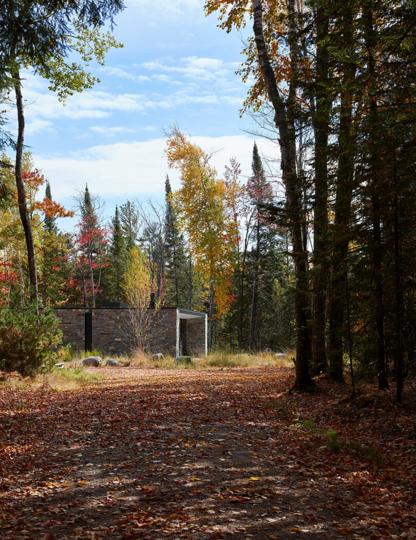 exterior shot from a distance of stone and glass lake house