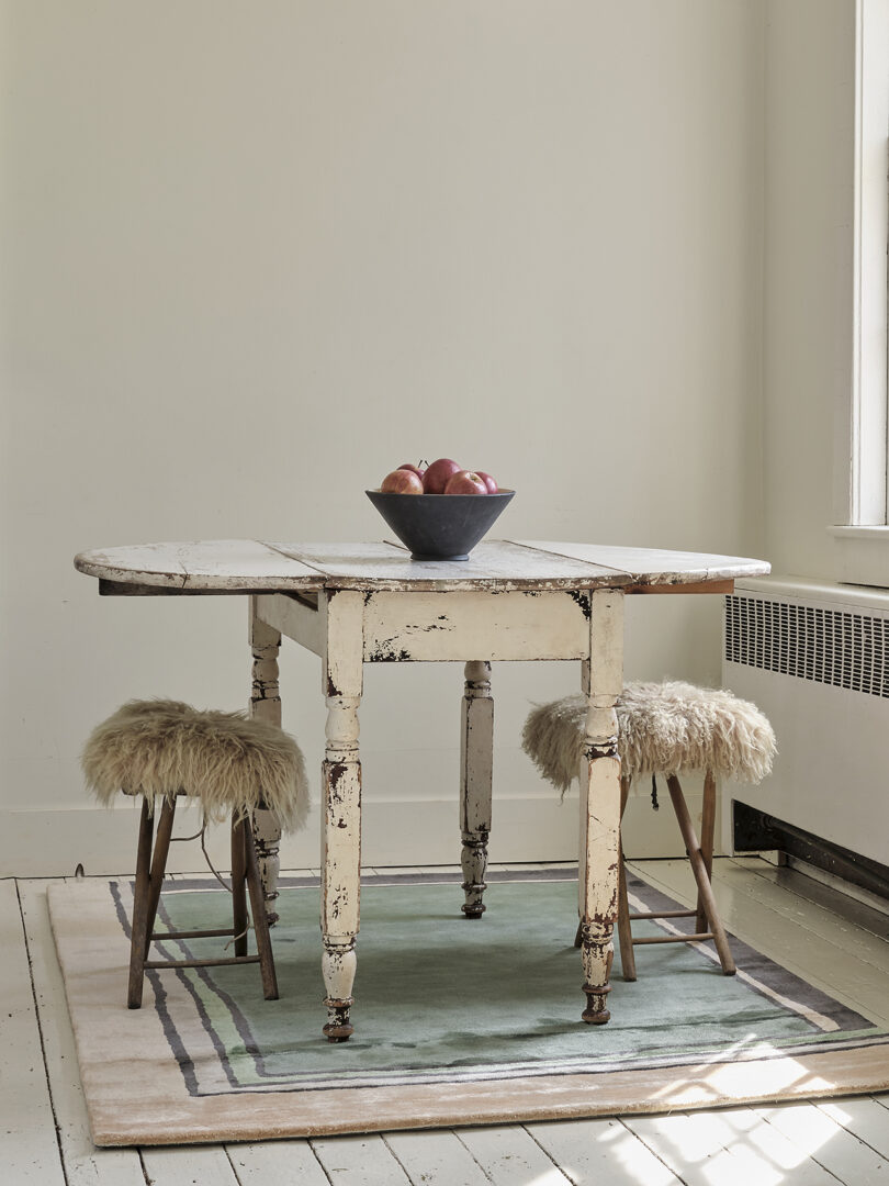 kitchen table and two stools on top of an abstract rectangular rug