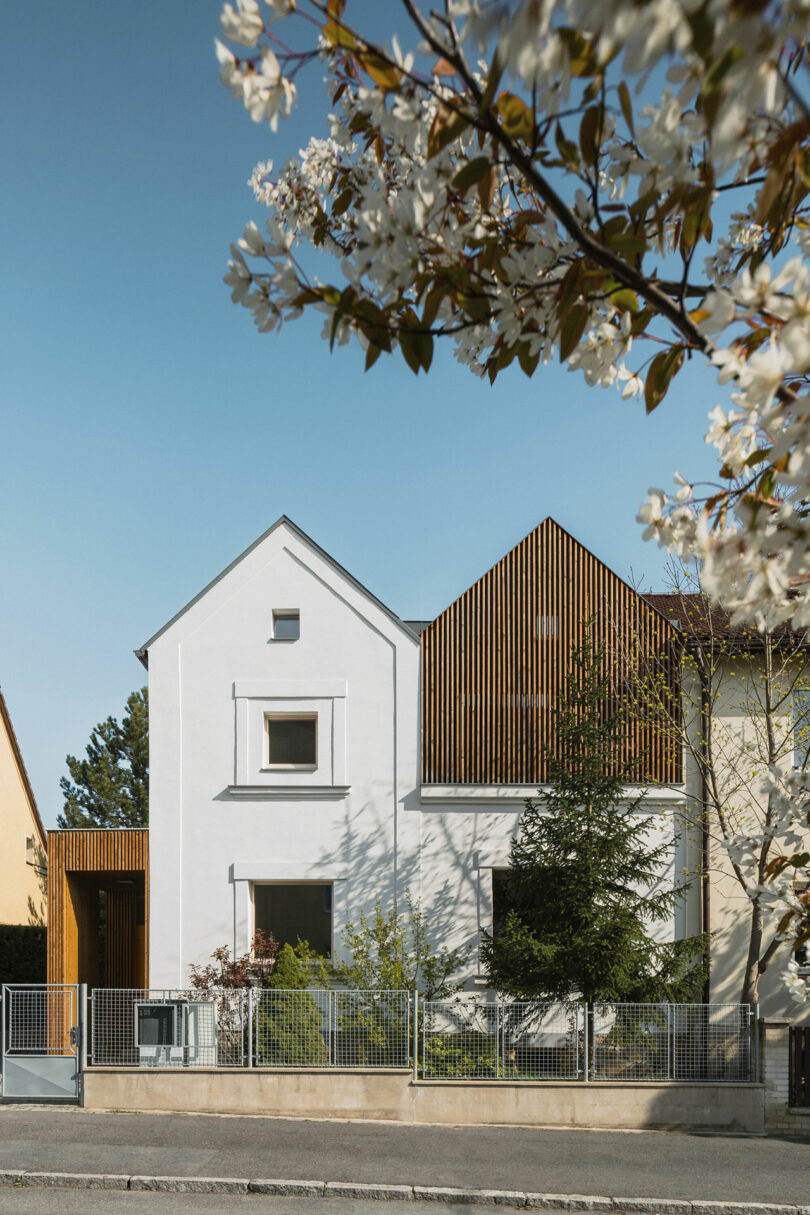 Front exterior view of modern wood slat and white double gabled house