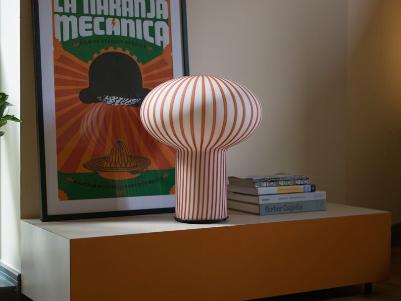 mushroom-shaped orange and white striped table lamp on a styled console