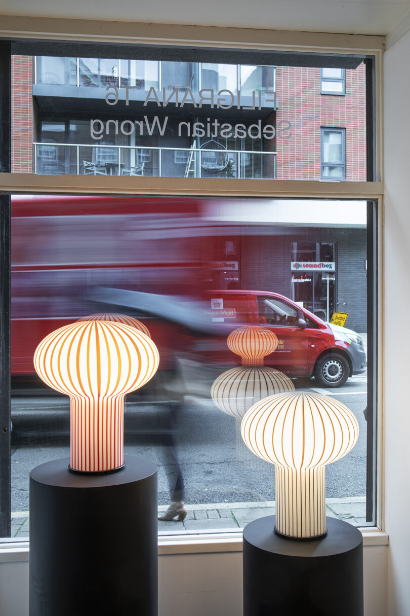 two mushroom-shaped striped table lamps on display in a window