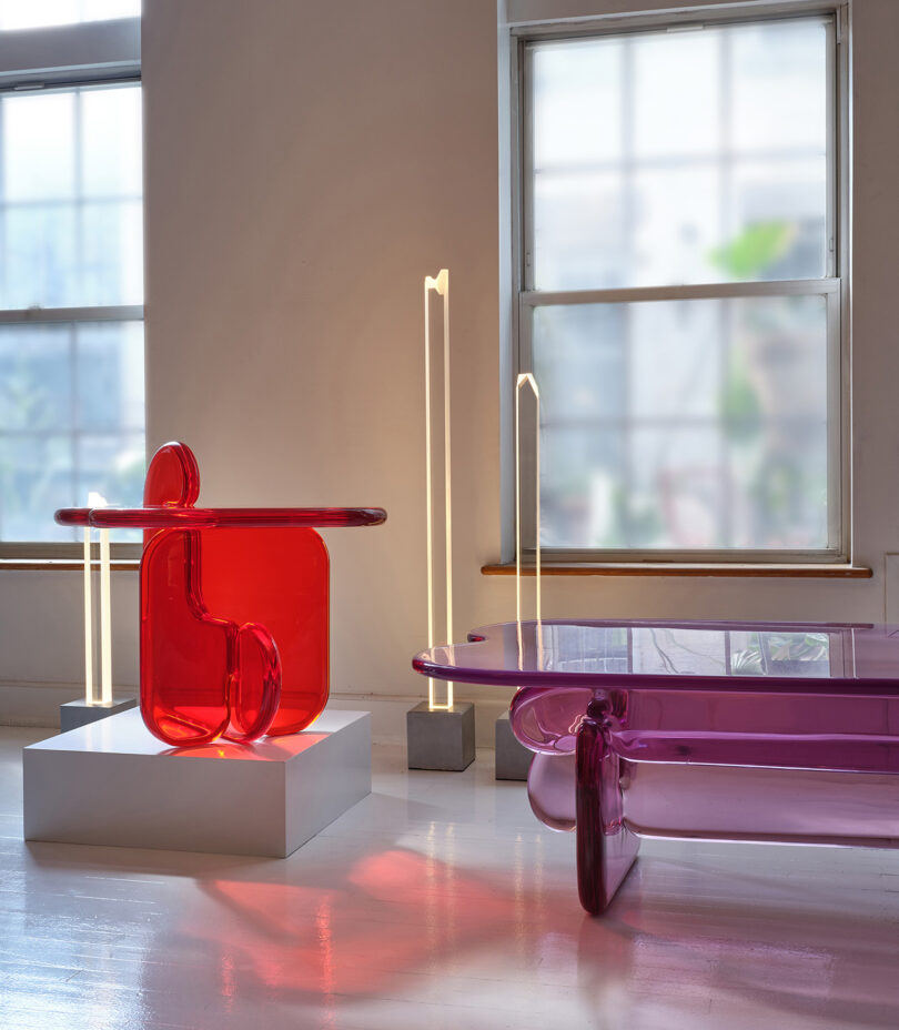 móveis de resina em exibição em uma galeria, mesa lateral vermelha e mesa de centro lilás