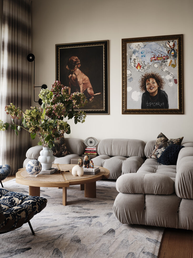 styled living space with bulbous greige sofa, a wood coffee table, and two large pieces of art