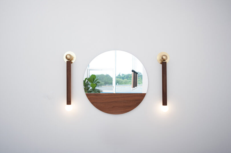 two black sconces flanking a round mirror