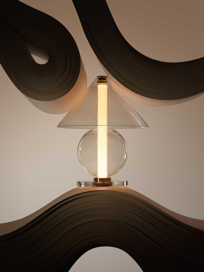 all glass lamp with round base and cone-shaped shade illuminated