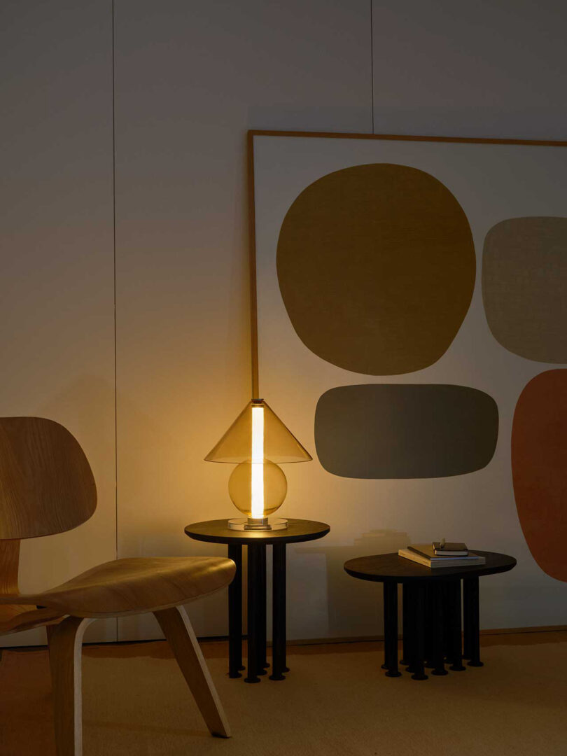all glass lamp with round base and cone-shaped shade illuminated in a styled living space