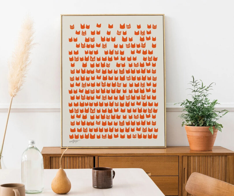 mid-century modern print of small orange cat heads in a styled space