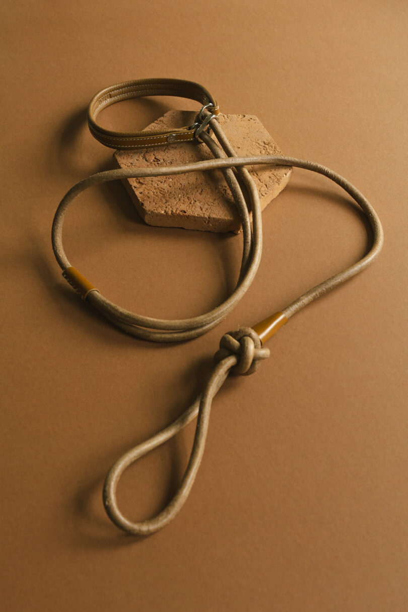 raw leather dog leash and matching collar set on a hexagonal tile and light caramel colored surface.