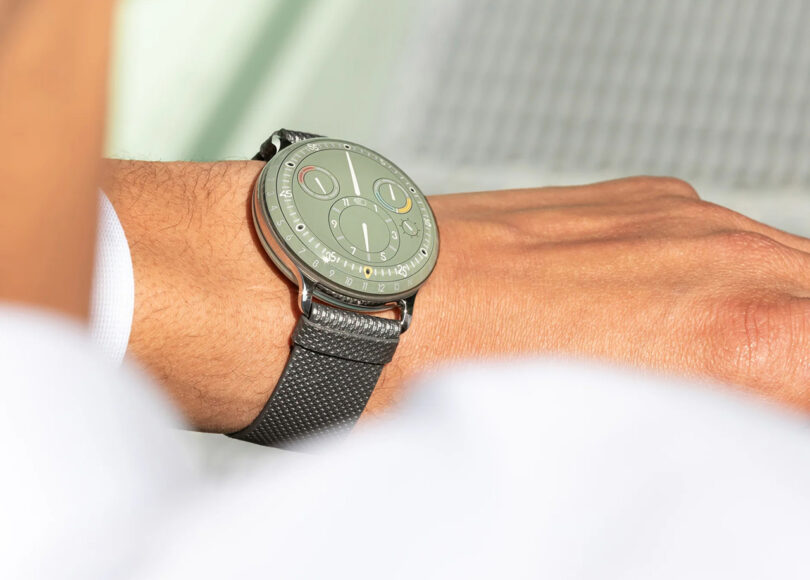 eucalyptus green modern watch with dark gray band on man's wrist.