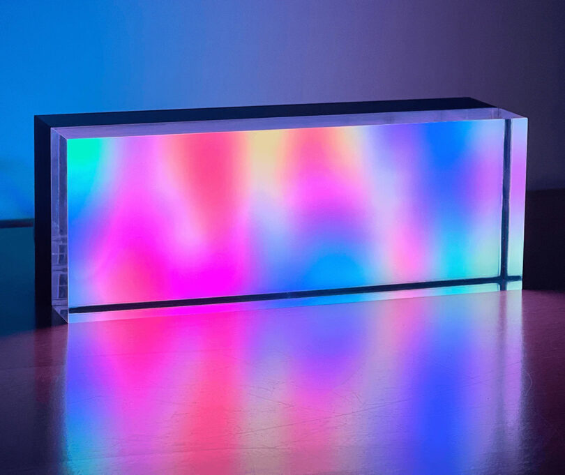 Rectangular block of glass embedded with colorful LED lights illuminating a spectrum of colors