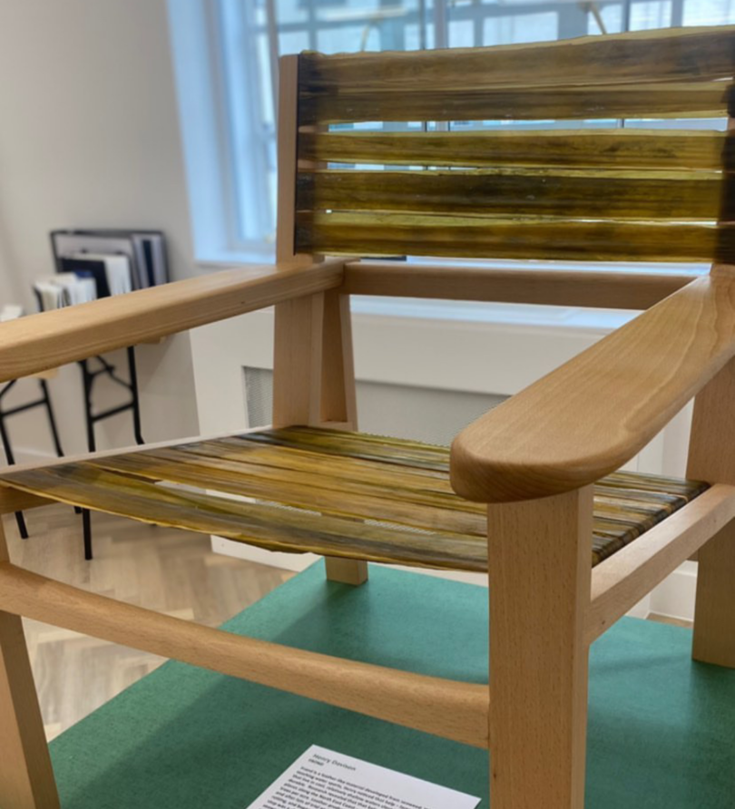 A wooden frames chair with kelp stretched across the frame to form the seat and back. 