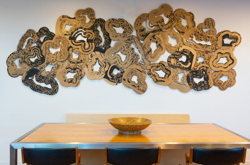 abstract layered wooden wall sculpture installed over a dining table