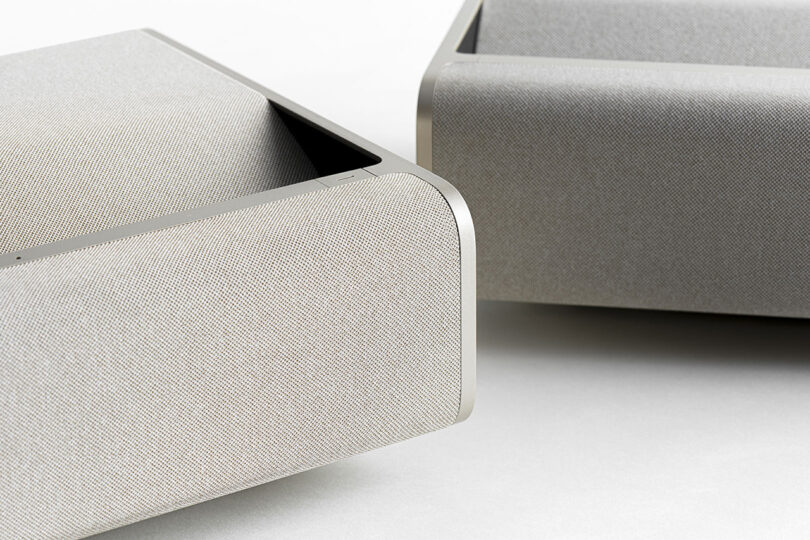 Angled view of two XGIMI ultra short throw projectors corners, showing the fabric cover design done in neutral tones.