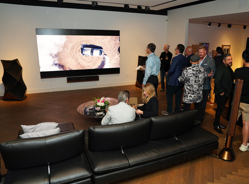 Group seated on leather sofa watching James Bond film on LG MAGNIT and Bang & Olufsen home theater bundle inside Bang & Olufsen’s Costa Mesa, California showroom in September 2023.