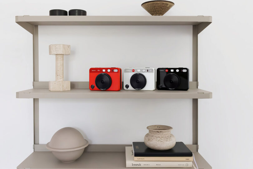 All three Leica SOFORT 2 in red, white and black, set on a three level shelf, each lined up front facing forward at an angle.