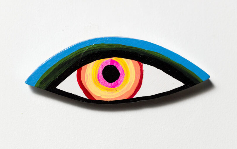pink, yellow, and blue eye painted on wood