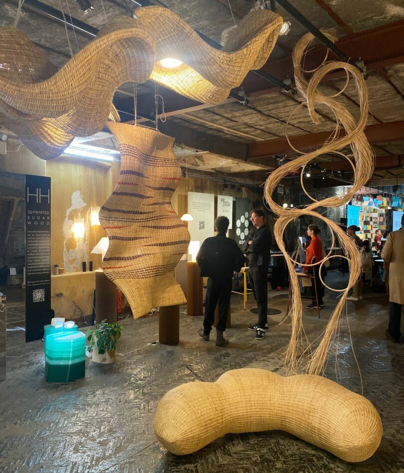 A series of sculptural wicker forms either hang from the ceiling or are placed on the floor of a rooftop warehouse space.