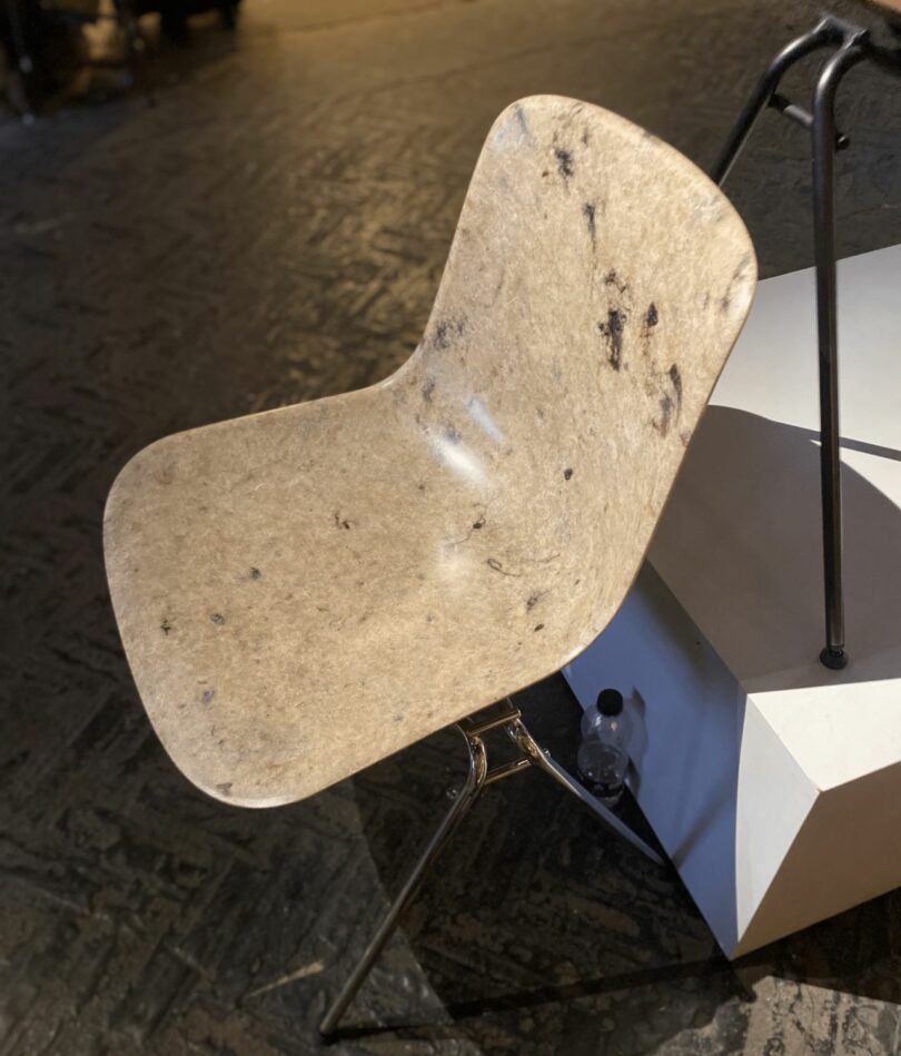A cream-colored chair on metal legs has darker brown sheep's wool patterns visible in its surface.