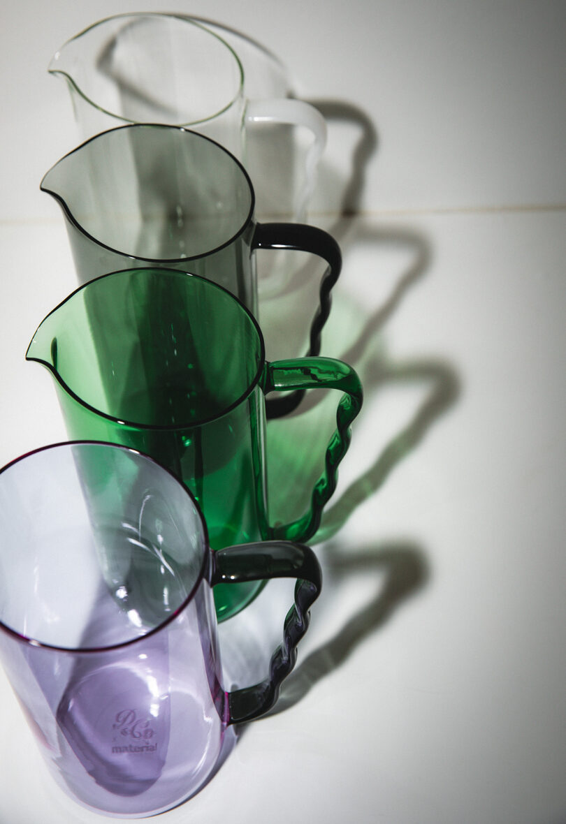 row of clear, grey, green, and lilac cocktail pitchers