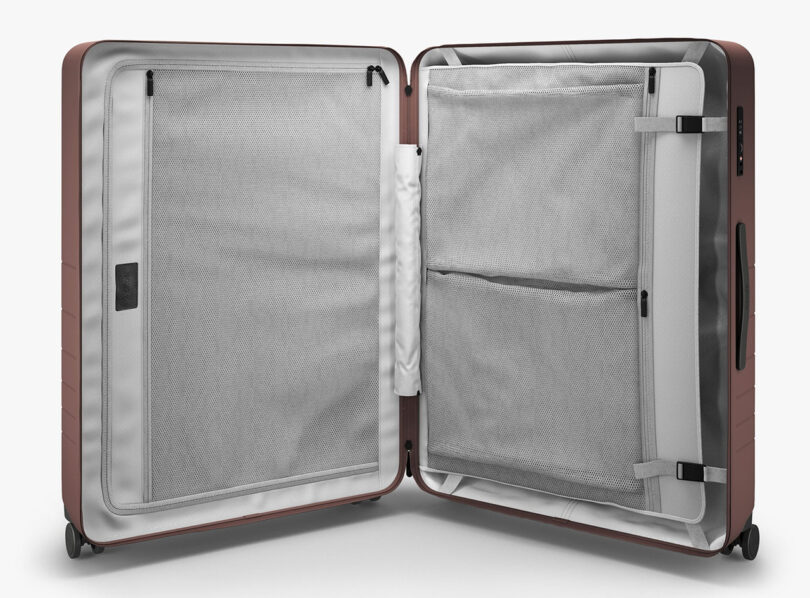 Monos Check-In hard case luggage opened, revealing the interior faux suede cover interior and sleeves.