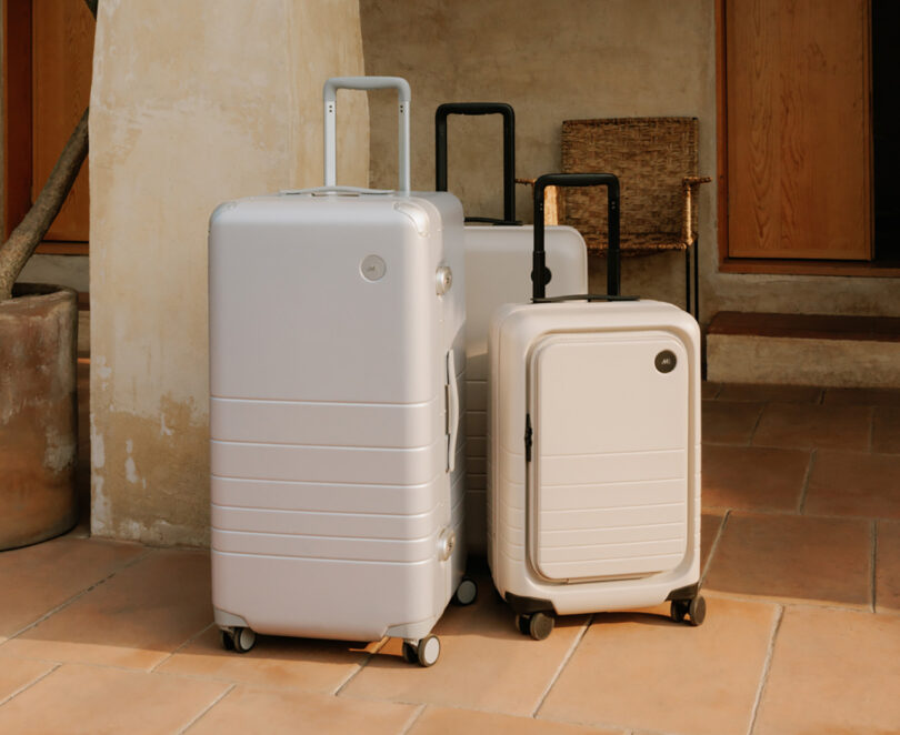 Hybrid trunk, Check-in and Carry-On Plus Monos hard case suitcases in Champagne finish, set vertically on their roller wheels with telescoping handles pulled up.
