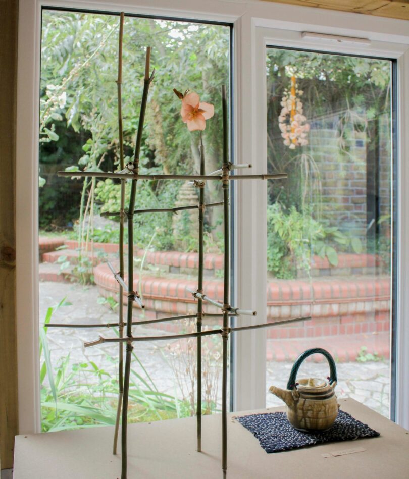 A bamboo frame sits in front of a window next to a teapot