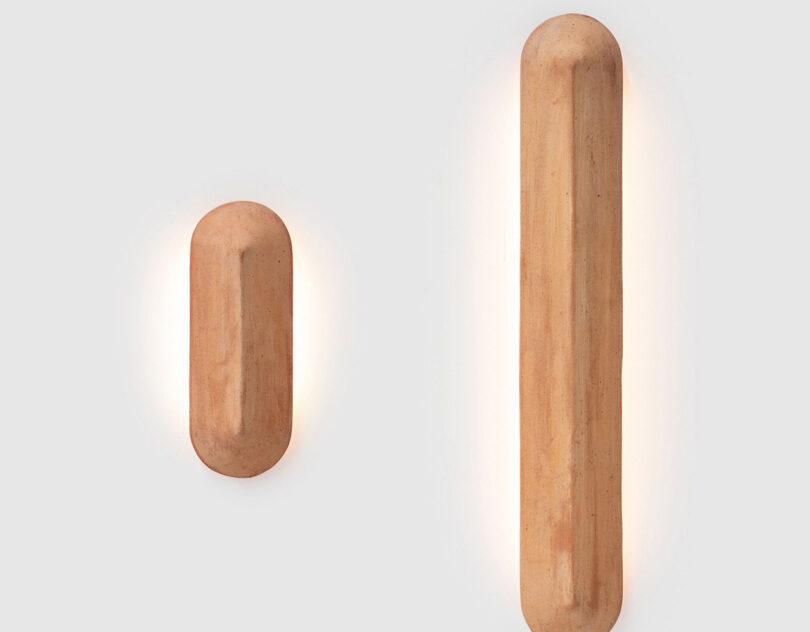 A simple, elongated wall light, offered in two lengths – 400mm and 900mm with a linear shield-like form characterized by a central sharp line or ‘pinch’ that allows light to fall differently on each side of the terracotta.
