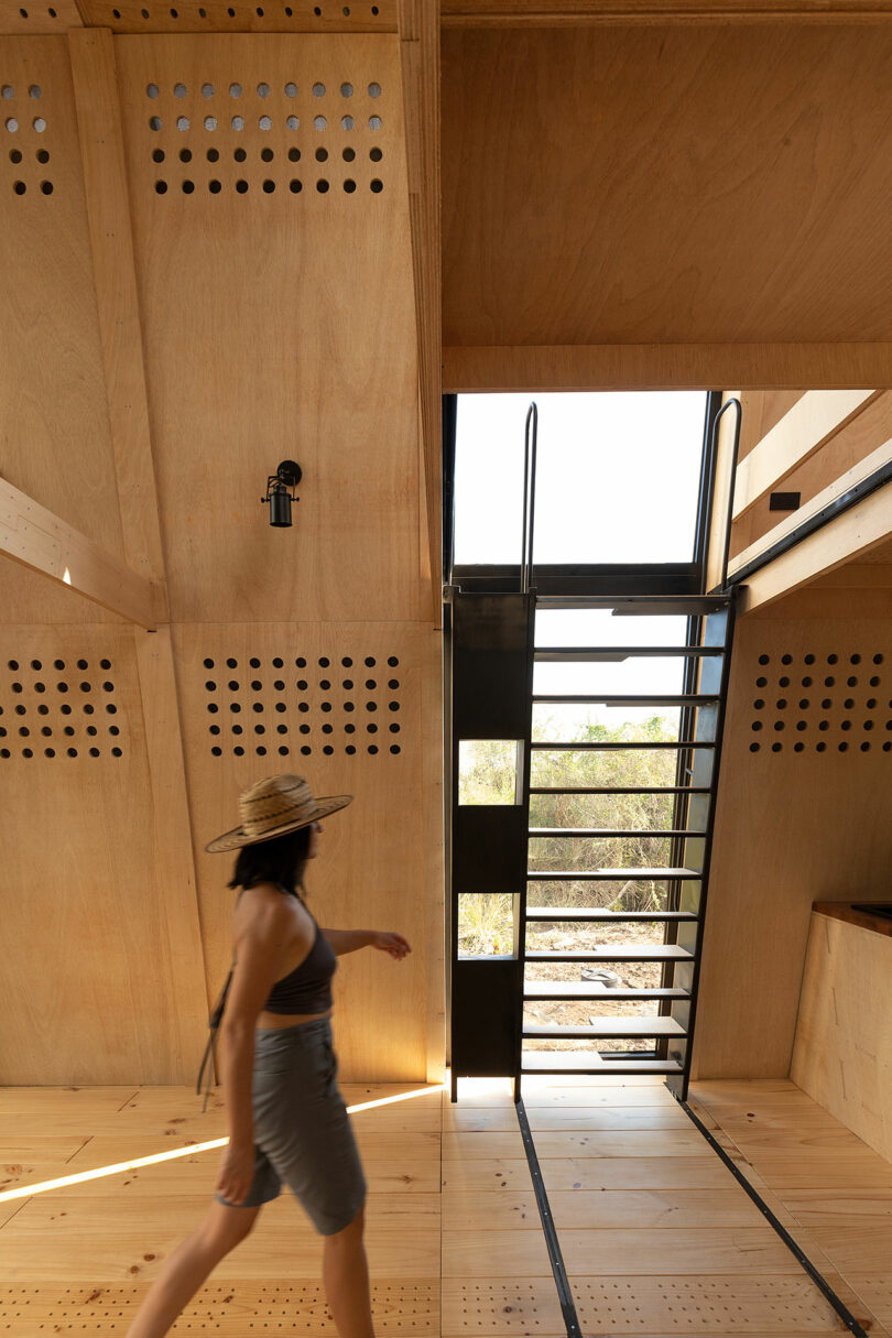 angled interior view of A-frame cabin with slanted wood walls and moving staircase