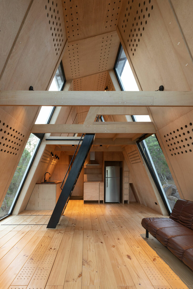 vista interior longa da cabine moderna com paredes de madeira inclinadas e decoração minimalista