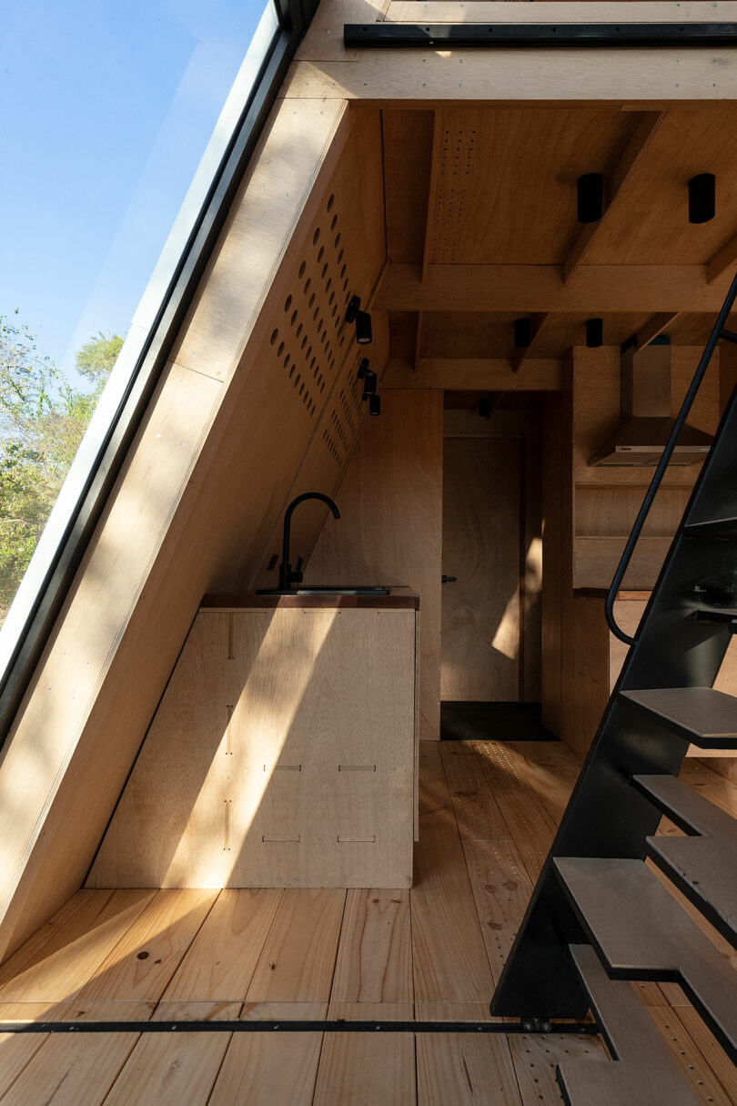 vista interior da cabana moderna com paredes de madeira inclinadas e decoração minimalista