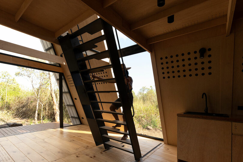 vista interior angular da cabine minimalista com mulher subindo a escada