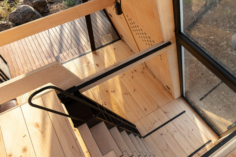 down shot from 2nd floor of minimalist cabin looking down ladder staircase