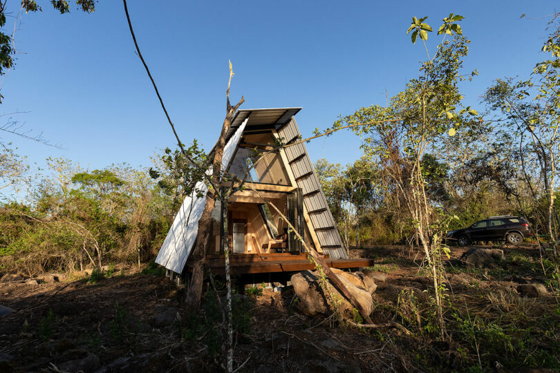 vista externa da cabana com telhado de zinco na floresta