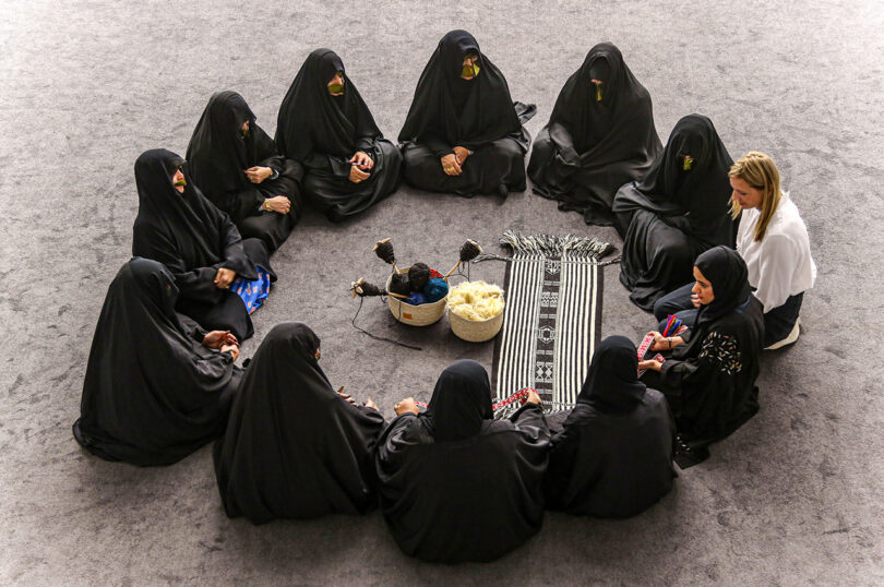 a circle of people sitting next to one another wearing black and one person wearing white
