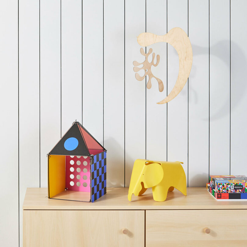 colorful house toy next to yellow elephant toy on dresser
