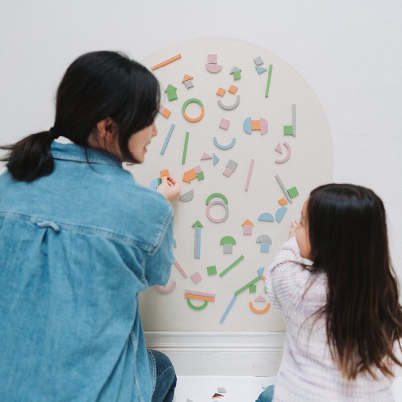 woman and child placing magnets on wall decal