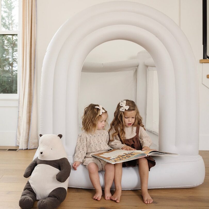 two girls sitting on white bounce house