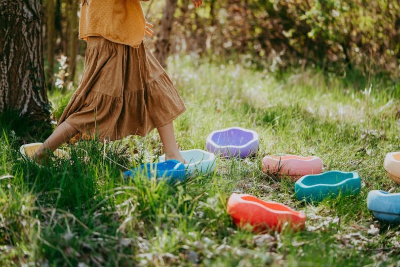 girl wearing a skirt stepping on toys placed in the grass