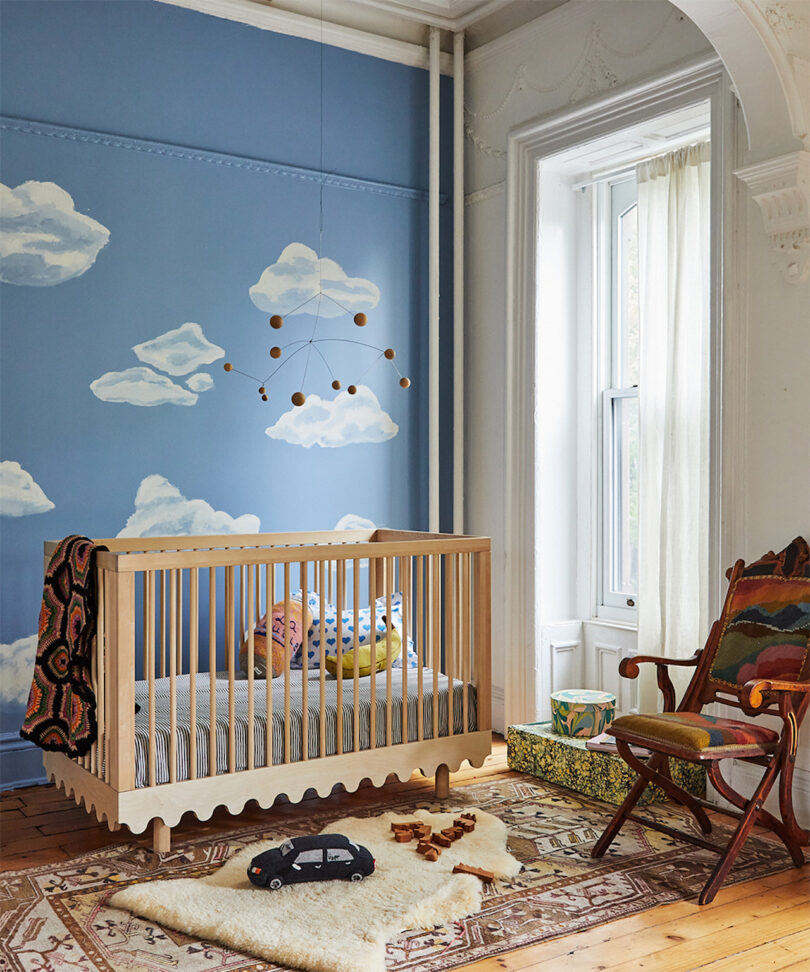 wavy wooden birch crib in a cloud wallpaper room