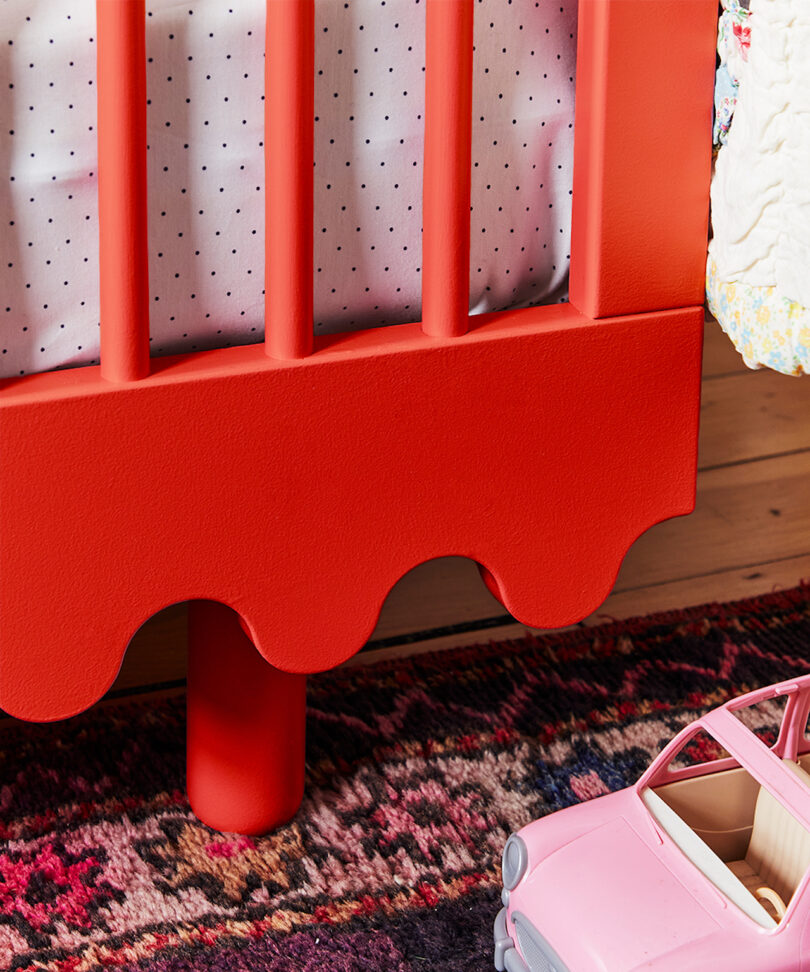 close up details of wave motif on red crib