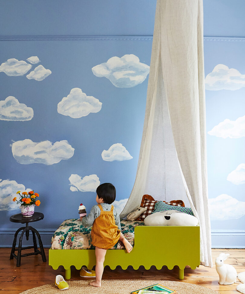 child climbing into wavy green toddler's bed
