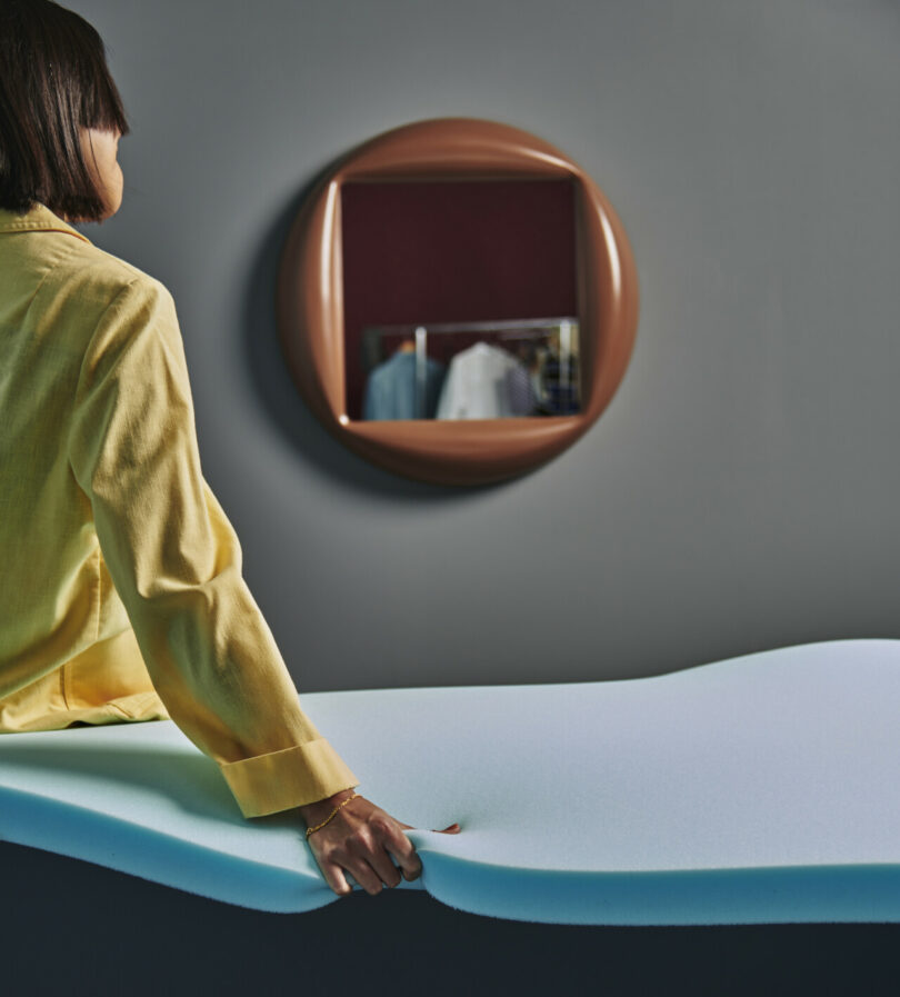woman in yellow shirt next to a brown mirror on the wall
