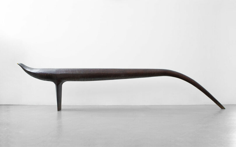 Profile of black bench that is vaguely bird like in shape.
