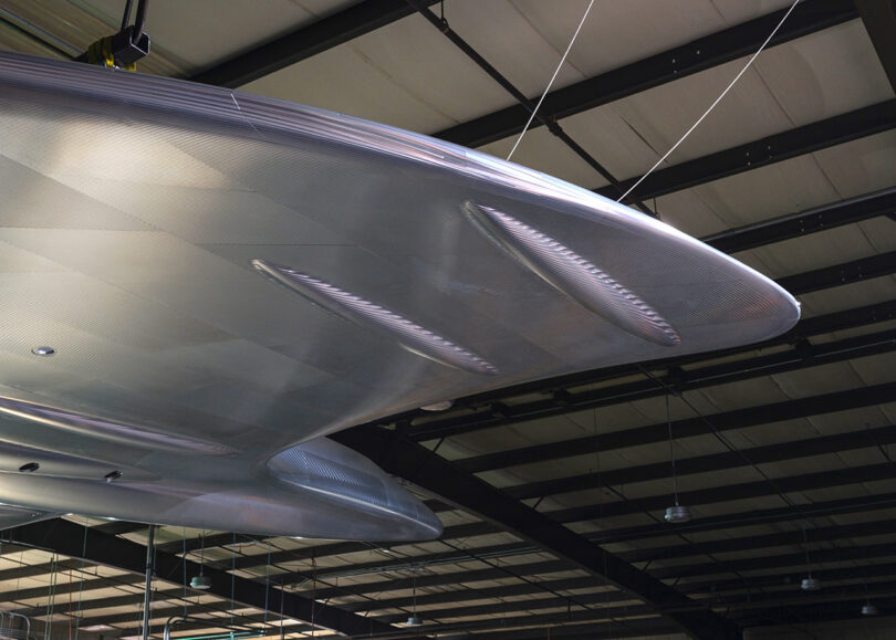 Detail of large polished aluminum sculpture of the Concorde jet plane secured above across the ceiling secured by cables.