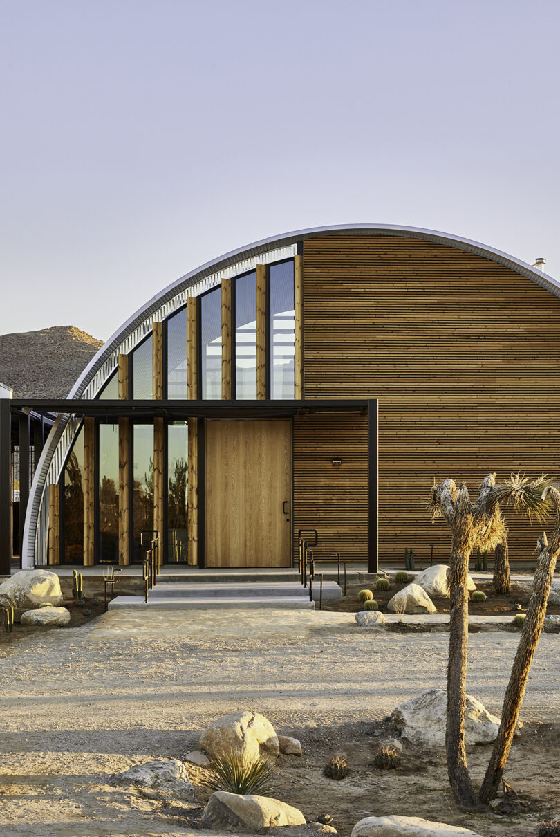 modern glass, wood, and metal hanger-shaped building in the desert